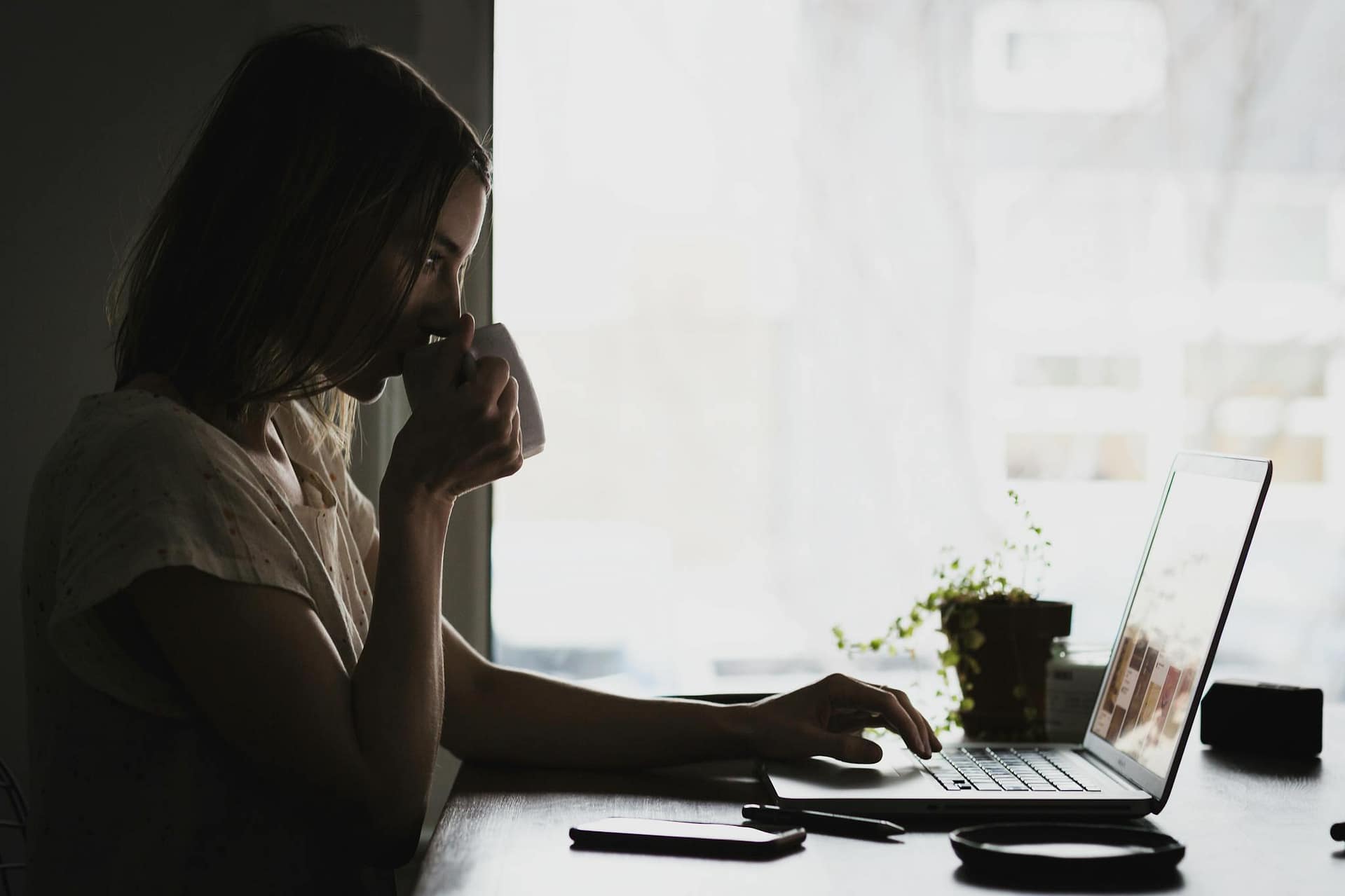 Woman sitting at home with a laptop and coffee while working on online ideas