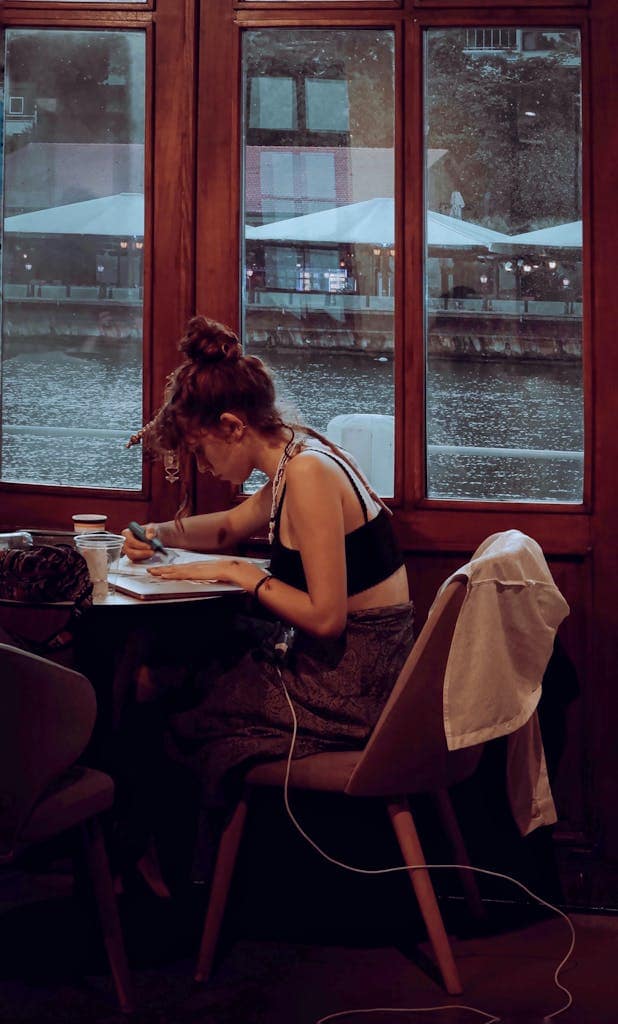 A young woman intensely studying at a café by the river, perfect for lifestyle or education themes.
